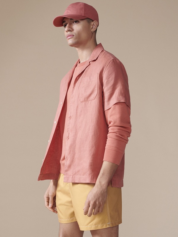 A model wearing all peach clothing, including a baseball cap, shirt and shorts